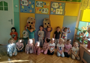 Dzieci z grupy pomarańczowej pozują do zdjęcia grupowego z wykonanymi przez siebie domkami
