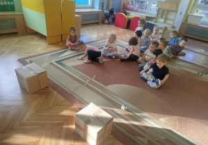 Dzieci w drużynach turlają kule z gazet do tekturowych pudelek