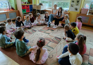 dzieci siedzą w kole, dziewczynki czytają książkę