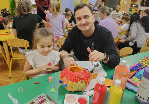 dzieci wraz z rodzicami ozdabiają dynie