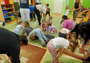 dzieci wraz z rodzicami wykonują asany podczas zabaw ruchowych