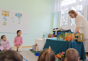 Dzieci słuchająi oglądają inscenizację bajki "Królowa Śniegu" opowiadanej przez prowadzącą warsztaty