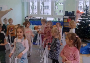 Dzieci tańczą do muzyki z Królowej Śniegu, w ręku trzymając białe wstążki