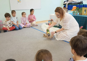 Dzieci słuchająi oglądają inscenizację bajki "Królowa Śniegu" opowiadanej przez prowadzącą warsztaty