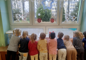 dzieci wypatrują przez okno Świętego Mikołaja