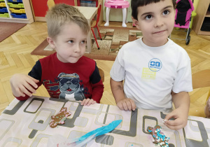 dzieci siedzą przy stole i ozdabiają pierniki