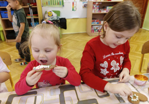 dzieci siedzą przy stole jedzą i ozdabiają pierniki