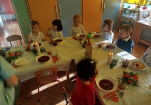 dzieci wspólnie siedzą przy świątecznym stole, spożywają potrawy