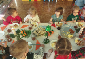 dzieci wspólnie siedzą przy świątecznym stole, spożywają potrawy