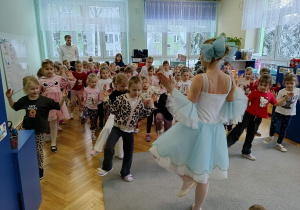 dziewczynki uczą się układu kroków jaki prezentuje baletnica