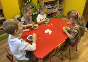 dzieci mieszają w miseczkach patyczkami składniki do wykonania kul do kąpieli,