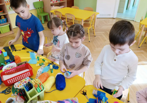 dzieci siedzą przy stolikach, wykonują kukiełki