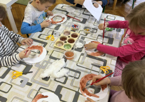 Dzieci przy stolikach wykonują pracę plastyczne