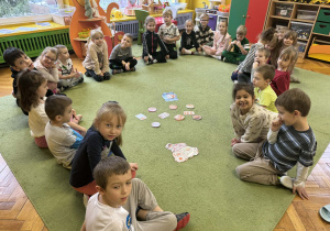Dzieci rozwiązują zadania matematyczne na dywanie