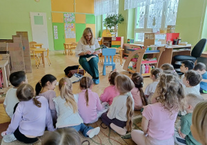 dzieci siedzą na dywanie - słuchają zagadek