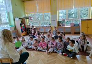 dzieci siedzą na dywanie - słuchają zagadek