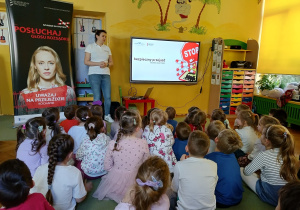 dzieci siedzą na dywanie, słuchają n informacji na temat kampanii