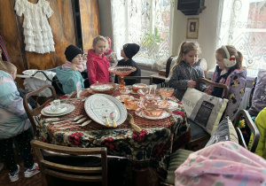 dzieci zwiedzają pomieszczenia mieszkalne w dawnych czasach