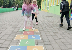 dziewczynki grają w klasy na tarasie przedszkolnym