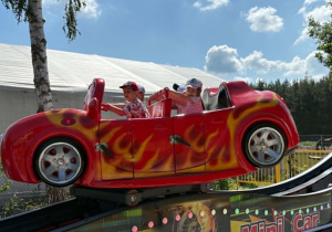 dzieci siedzą w ruchomym aucie i kręcą się w koło