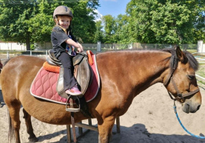 Jazda konno, dziecko siedzi na koniu a Pani prowadzi konia.