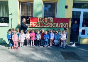 Grupa żółta pozuje do zdjęcia grupowego na tarasie przedszkolnym