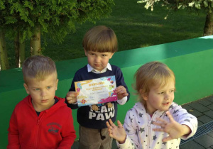 Dzieci stoją na tarasie z dyplomami