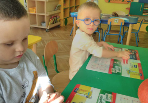 Chłopcy siedzą przy stoliku i ugniatają masę solną