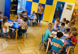Dzieci malują farbami wiewiórkę z drewna