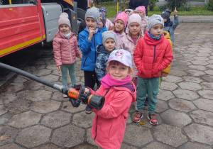 Chętne dzieci trzymają wąż strażacki