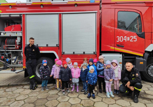 Dzieci z grupy srebrnej pozują do zdjęcia grupowego, w tle wóz strażacki