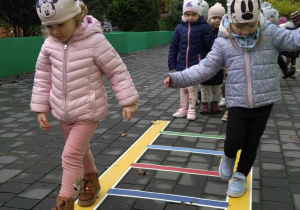 Dzieci ustawione parami po kolei chodzą po drabince