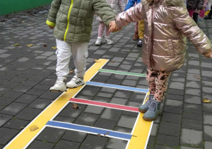 Dzieci ustawione parami po kolei chodzą po drabince