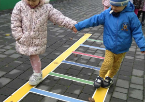 Dzieci ustawione parami po kolei chodzą po drabince