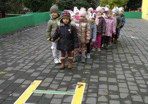 Dzieci stoją na tarasie, słuchają objaśnień nauczyciela