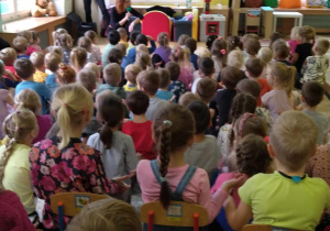 dzieci siedzą na dywanie przysłuchując się utworom ze znanych bajek