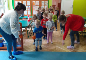 dzieci wykonują zabawy ruchowe przygotowane przez rodziców z grupy czerwonej