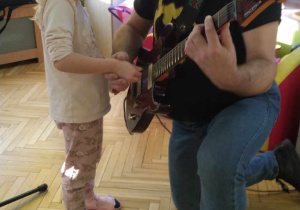 Dziewczynka próbuje zagrać na gitarze