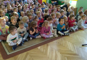 Dzieci siedzą na dywanie, słuchają muzyki
