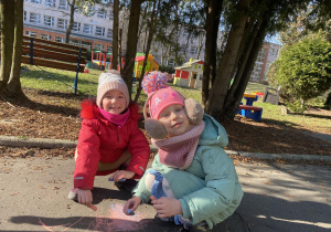 Dziewczynki rysują kredą po chodniku