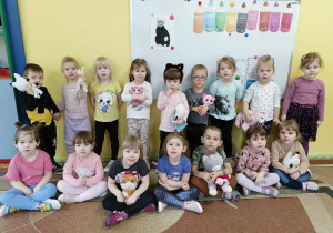 Dzieci pozują do zdjęcia grupowego ze swoimi przytulankami kotkami