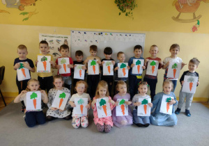 Dzieci pozują do zdjęcia grupowego z wykonanymi pracami plastycznymi