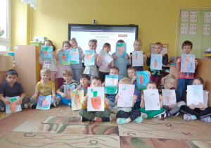Dzieci pozują do zdjęcia grupowego wraz z wykonanymi pracami