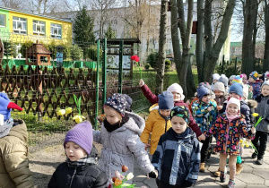 Dzieci idą parami, w rękach trzymają kwiaty