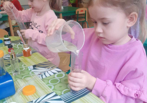 Dziewczynka nalewa wodę do probówki