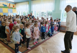 Dzieci stoją na dywanie, pokazują ruchem piosenkę