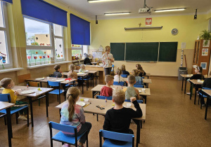 Dzieci siedzą w ławkach.