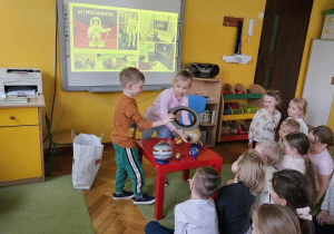 Franek i Lena pokazują zdjęcia i modele planet.