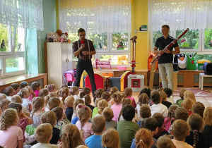 Dzieci siedzą w sali, słuchają gry na fagocie