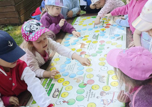 dzieci zapoznają się z grą dydaktyczną umieszczoną w ptasim zakątku